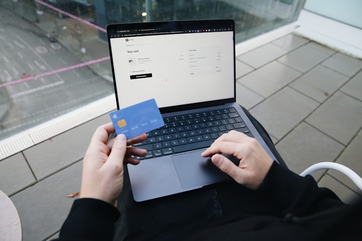 Person holding a bank card while using a laptop to make a transfer